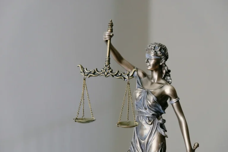 Estátua da justiça com venda nos olhos e balança, simbolizando imparcialidade e direito.