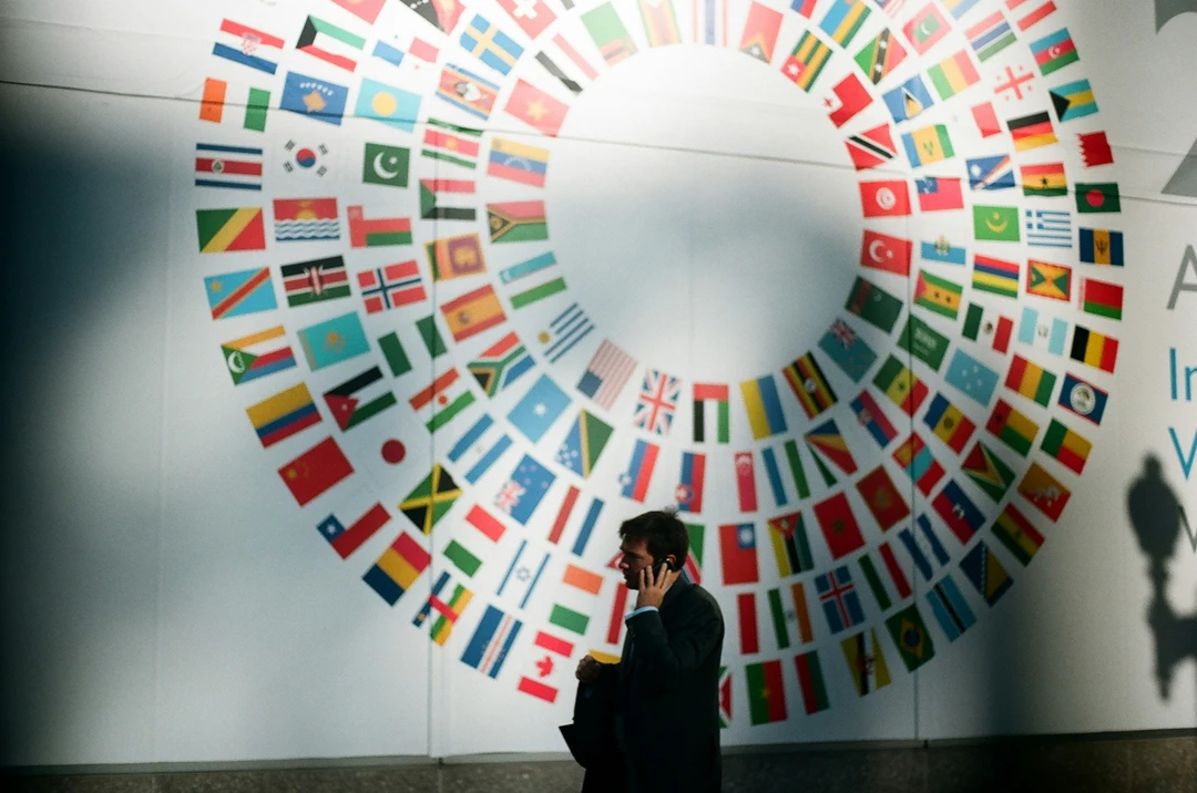 Painel circular com bandeiras de vários países em espaço interno internacional.